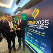 A imagem mostra dois homens de terno escuro posando para a foto em um evento. Ambos estão sorrindo e segurando um troféu com o logotipo do evento. Ao fundo, há um grande painel com o texto:
"CBME 2025 – I Congresso Brasileiro de Minas e Energia
22 SET | BRASÍLIA – DF
CASA DA ENERGIA, LAGO SUL"
Abaixo do título principal, há diversos logotipos de instituições apoiadoras do evento, como EPE, SEBRAE, ANM, ABPIP, IBRAM, IDP, ABiogás, entre outros.
O ambiente parece ser uma sala de conferências ou auditório, com iluminação clara e pessoas ao fundo interagindo.