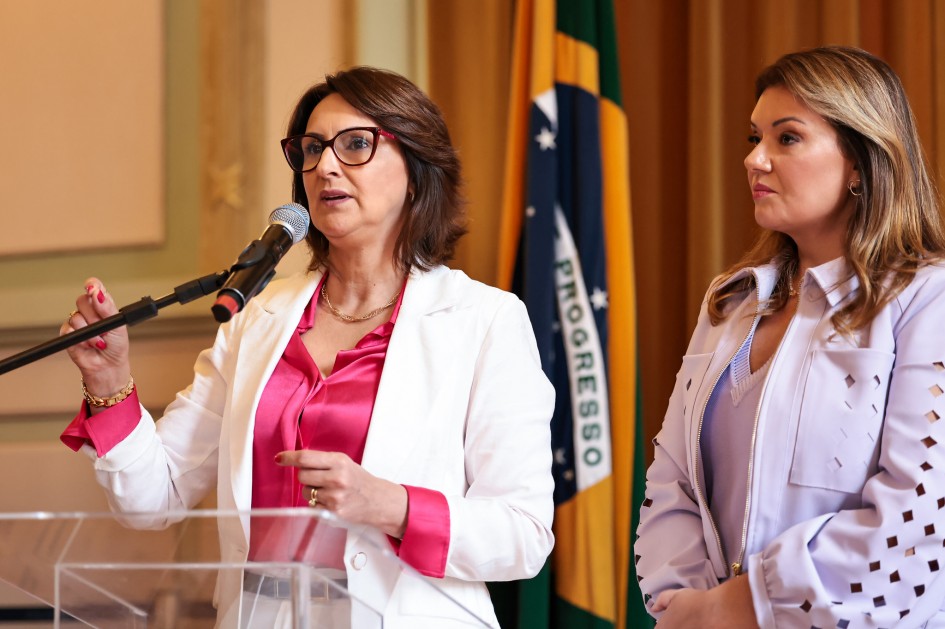 Secretária Fábia Richter discursa ao microfone. Atrás dela, está a secretária-adjunta Viviane Nery Viegas.