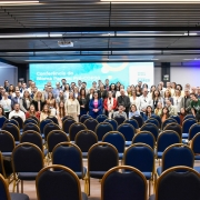 A imagem mostra uma foto coletiva com dezenas de pessoas reunidas no palco e à frente dele, posando para registro oficial. Ao fundo, a tela exibe o texto “Conferência do Bioma Pampa – Pré-COP30” e o logotipo do Fórum Gaúcho de Mudanças Climáticas (FGMC).