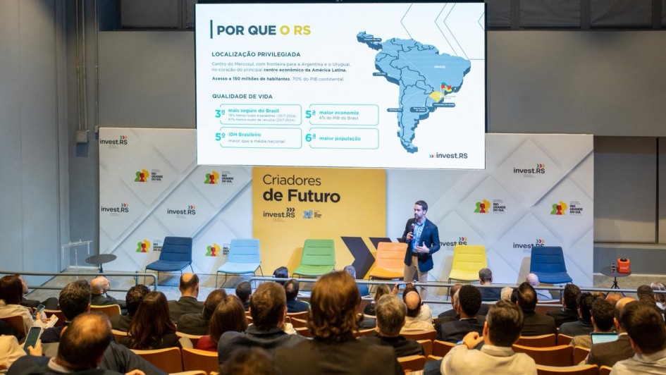 O governador Eduardo Leite apresenta o painel durante evento em São Paulo. Ele fala diante de um auditório cheio, com slide projetado ao fundo mostrando mapa do Brasil e indicadores de economia e qualidade de vida do Estado.