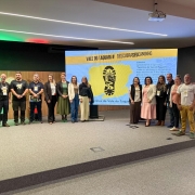 Foto posada num palco, com treze pessoas de pé. Ao fundo, há um telão com os escritos "Vale do Taquari, descubra seu caminho".