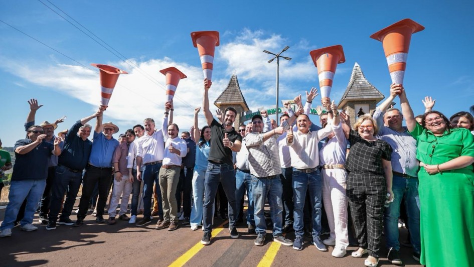 Foto posada de Leite ao centro, com várias pessoas ao redor, erguendo cones de trânsito na estrada, em comemoração.