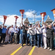 Foto posada de Leite ao centro,  com várias pessoas ao redor, erguendo cones de trânsito na estrada, em comemoração.