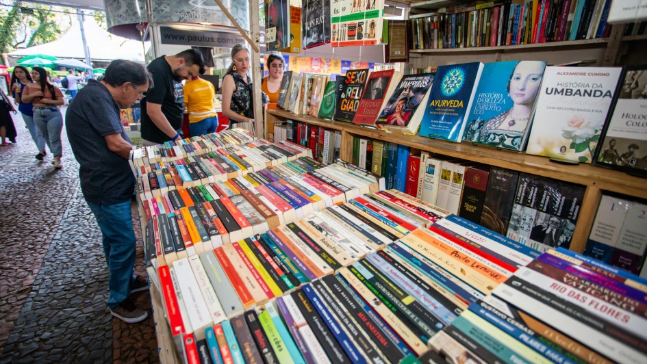 Foto exibe pessoas procurando livros em estande da Feira do Livro