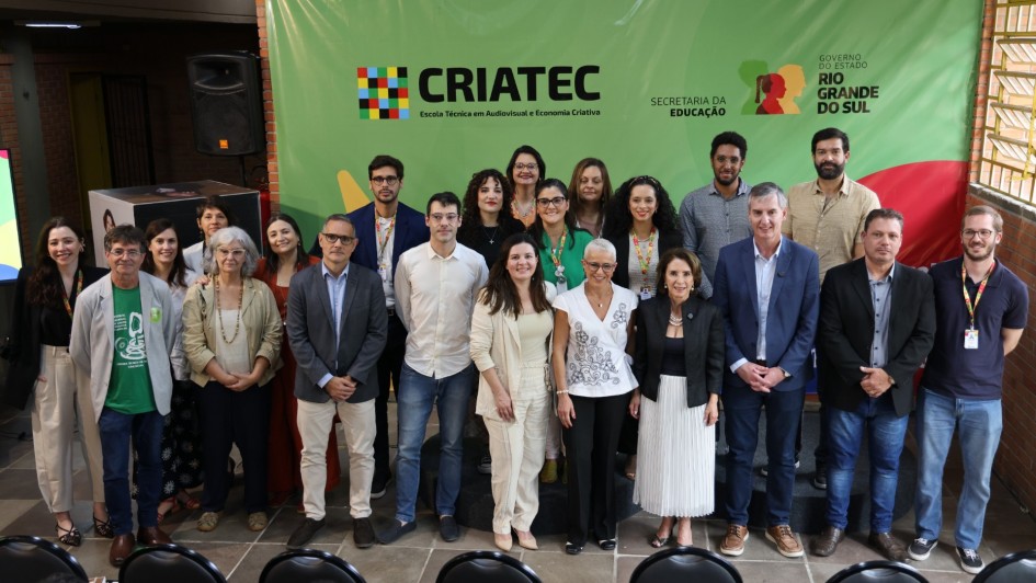 oto de grupo registra o lan&ccedil;amento do plano de ocupa&ccedil;&atilde;o da Escola T&eacute;cnica CRIATEC, primeira voltada ao audiovisual e &agrave; economia criativa no Rio Grande do Sul. A imagem mostra autoridades, educadores e profissionais da cultura reunidos diante do painel institucional da CRIATEC, da Secretaria da Educa&ccedil;&atilde;o e do Governo do Estado do Rio Grande do Sul. Todos posam sorridentes em ambiente interno, com decora&ccedil;&atilde;o colorida e ilumina&ccedil;&atilde;o natural.