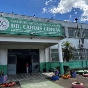 A imagem mostra a fachada de uma escola, em tons verdes e brancos. Na frente, se lê "Instituto Estadual de Educação Dr. Carlos Chagas". 
