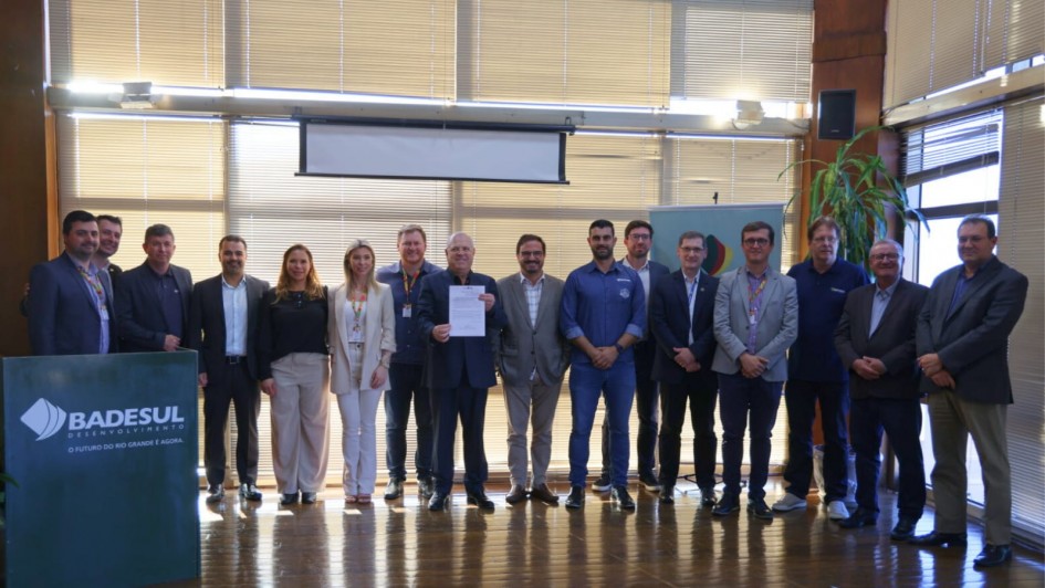 Foto mostra 16 pessoas perfiladas, durante ato para assinatura para o Programa Bônus Mais Leite. Ao centro, secretário Vilson Covatti, segura documento