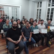 Foto mostra grupo de pessoas sentadas em auditório. São participantes do Desafio Literário 2025, promovido pela Secretaria da Cultura. À frente, com diplomas em mãos, estão os três vencedores 