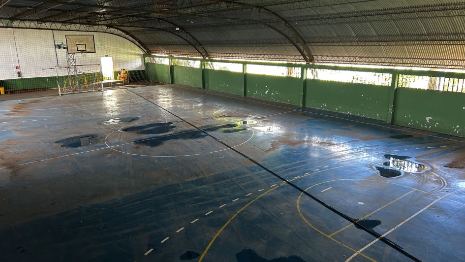 Imagem mostra interior de ginásio de escola com poças de água no piso por conta de problemas em telhado que será reformado