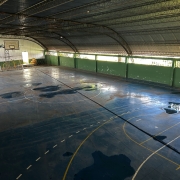 Imagem mostra interior de ginásio de escola com poças de água no piso por conta de problemas em telhado que será reformado