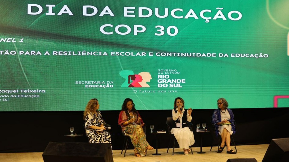 A imagem mostra quatro mulheres sentadas em cadeiras em um palco. Ao fundo, há um painel onde se lê "Dia da Educação COP30", o título do painel e as marcas da Secretaria da Educação e do governo do Estado do Rio Grande do Sul.