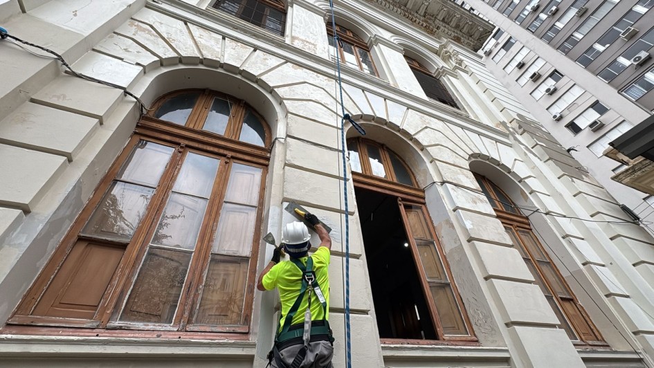 Foto mostra operário trabalhando no restauro da parede externa do Colégio Paula Soares, em Porto Alegre
