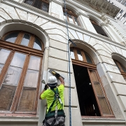 Foto mostra operário trabalhando no restauro da parede externa do Colégio Paula Soares, em Porto Alegre