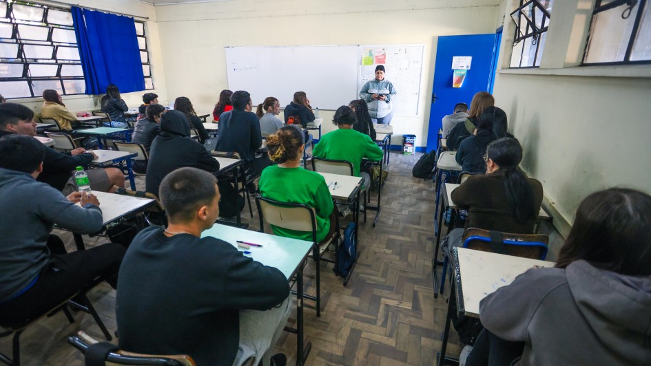 Foto mostra sala de aula com alunos acompanhando aula de professora.