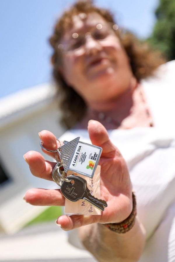Foto mostra mulher segurando chave de sua casa nova