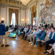 Foto mostra governador Eduardo Leite e pelo vice Gabriel Souza, na reunião do Conselho do Plano Rio Grande, ambos em pé falando aos participantes, no Palácio Piratini.