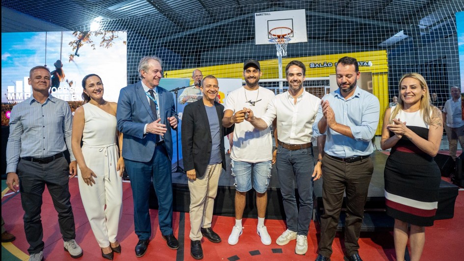 Um grupo de autoridades e convidados posa em uma quadra esportiva coberta durante um evento de entrega de moradias. No centro da imagem, pessoas sorriem e seguram simbolicamente uma chave.
O governador Eduardo Leite aparece na foto — ele está ao centro-direita, de camisa branca, sorrindo.