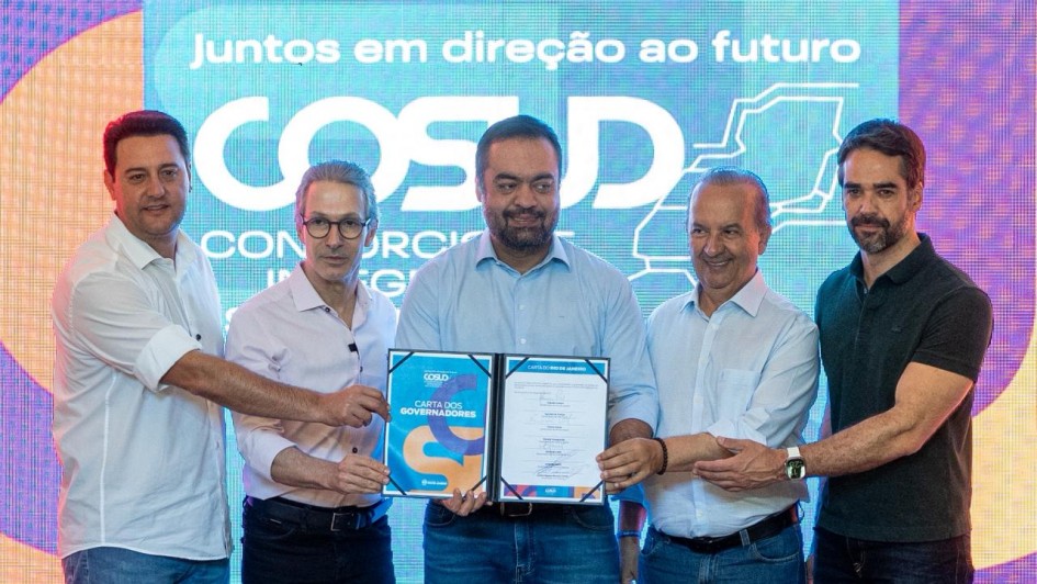 Cinco homens em traje formal com segurança documento conjunto diante de tela com mensagem sobre integração regional.