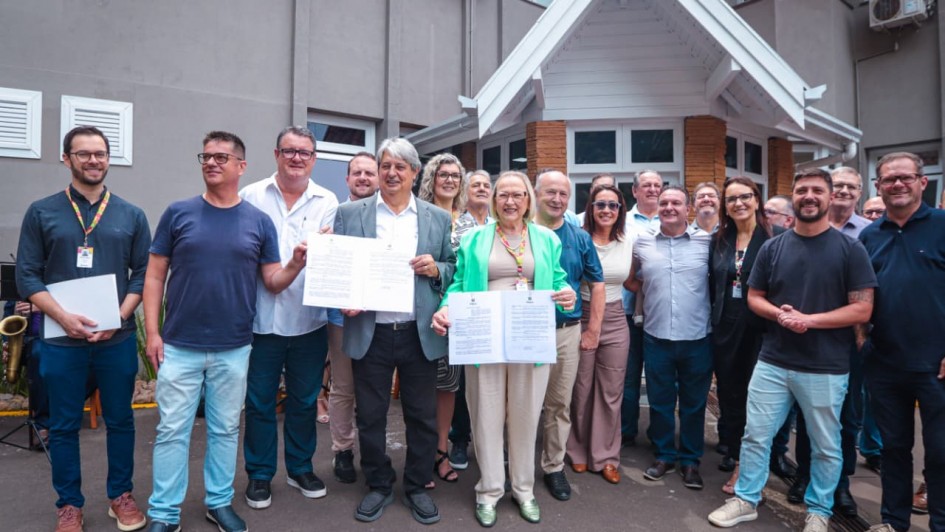 Foto mostra grupo de pessoas em ato de assinatura, tendo, ao centro, a secret&aacute;ria da Sa&uacute;de Arita Bergmann 