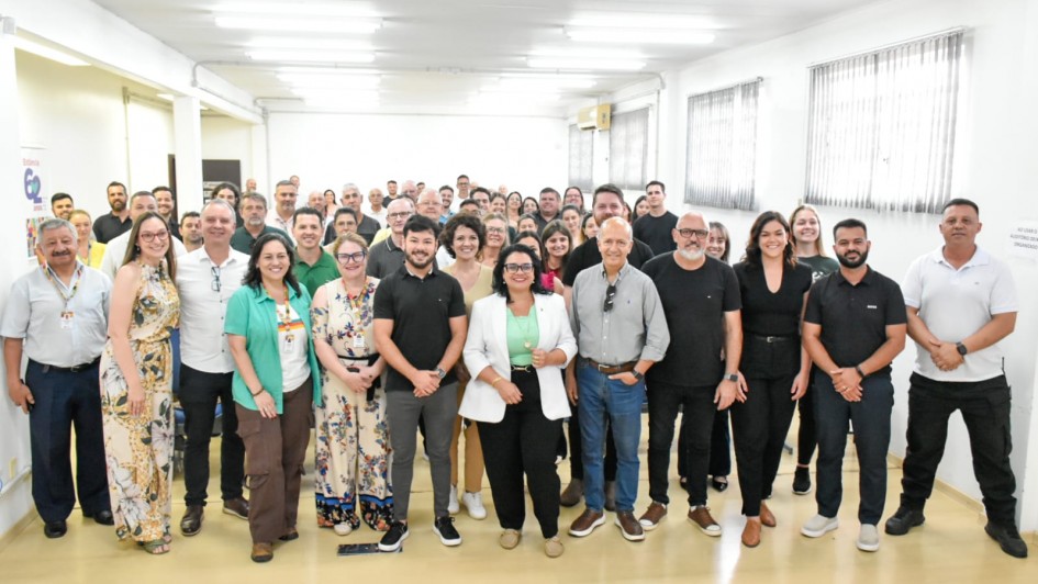 Foto posada em sala fechada, com mais de 50 pessoas de p&eacute; de frente para a c&acirc;mera. &Agrave; frente, com outras pessoas ao lado, aparece a secret&aacute;ria Marjorie, ao centro.