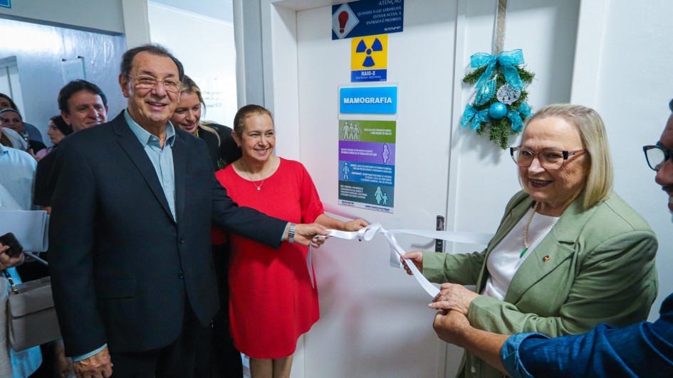 Secret&aacute;ria Arita e integrantes do hospital desatam fita inaugural branca em frente a porta da nova UTI adulto.