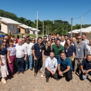 Foto mostra grupo reunido em frente &agrave;s casas com governador e secret&aacute;rios. 