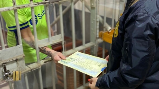 Foto mostra entrega de documento pela grade da pris&atilde;o
