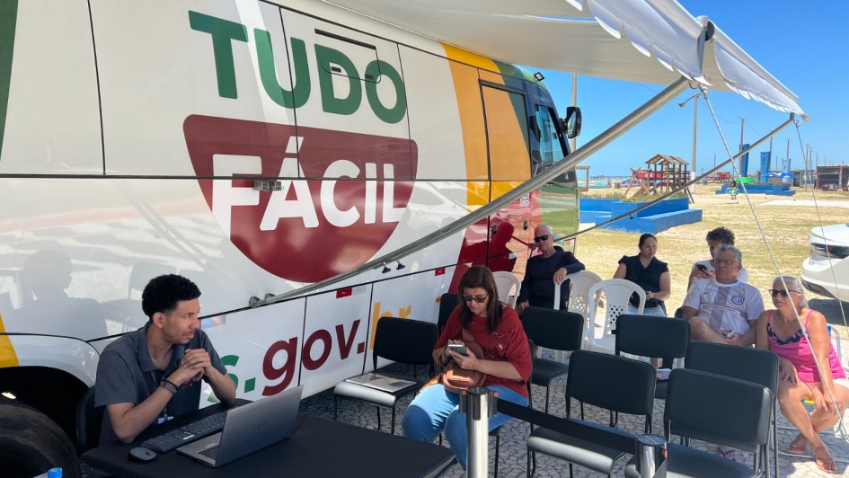 Foto mostra unidade do Tudo F&aacute;cil m&oacute;vel e pessoas aguardando atendimento