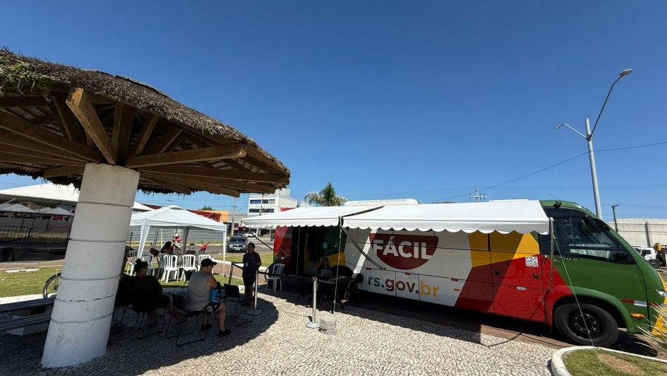 Imagem ao ar livre no litoral, com destaque para um &ocirc;nibus do Tudo F&aacute;cil, adesivado com o nome do programa e nas cores da bandeira do RS (amarelo, vermelho e verde).