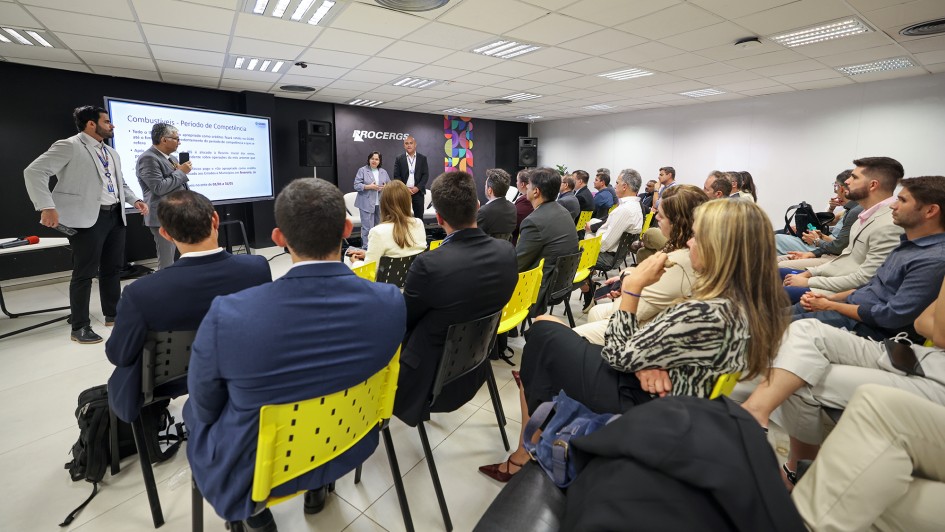 Foto mostra ao fundo a secret&aacute;ria Pricilla Santana e outros tr&ecirc;s homens em p&eacute;, diante de uma plateia sentada. 