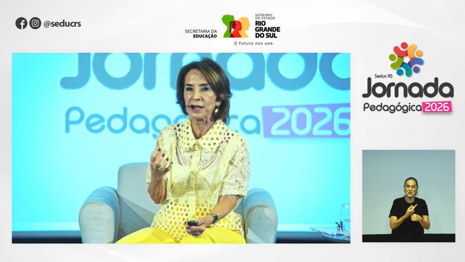 Reprodu&ccedil;&atilde;o da transmiss&atilde;o da live no Youtube. A imagem mostra a secret&aacute;ria da Educa&ccedil;&atilde;o sentada, falando ao microfone. Em uma miniatura, v&ecirc;-se a tradutora de Libras. Tamb&eacute;m se pode ler "Jornada Pedag&oacute;gica 2026 - Seduc RS" e a marca do Governo do Rio Grande do Sul.