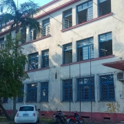 Prédio de três andares com várias chanelas, com paredes e pinturas desgastadas