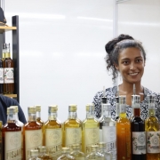 Foto de duas mulheres atr&aacute;s de uma banca de bebidas. Elas sorriem.