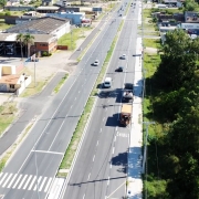 Foto a&eacute;rea de uma estrada duplicada de m&atilde;o dupla. Alguns carros passam por ela. &Agrave; direita, h&aacute; uma mata.