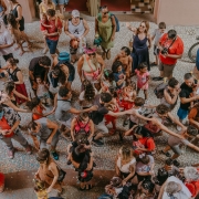 Imagem a&eacute;rea de diversas crian&ccedil;as e adultos pulando carnaval na rua. 