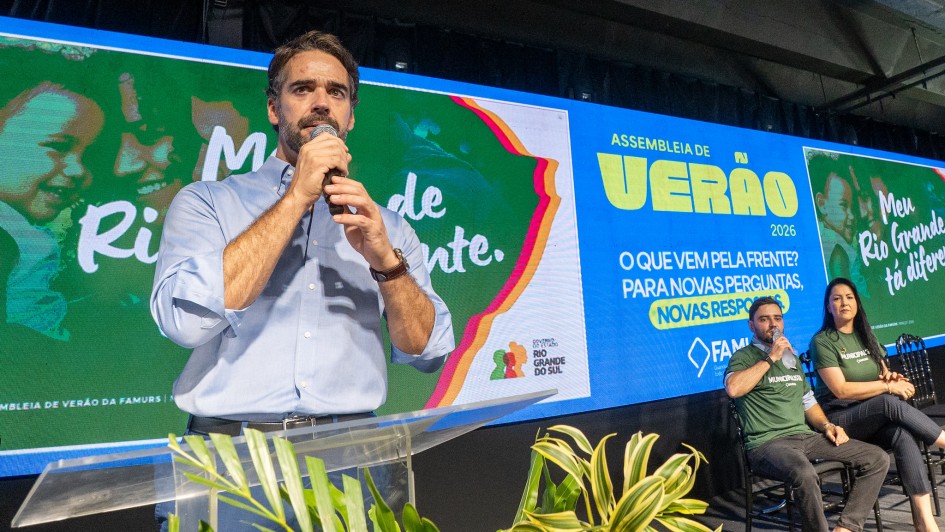 A imagem mostra o governador falando ao microfone em um palco com um tel&atilde;o onde se l&ecirc; "Assembleia de Ver&atilde;o 2026 - O que vem pela frente? Para novas perguntas, novas respostas" e "Meu Rio Grande est&aacute; diferente". 