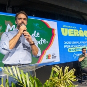 A imagem mostra o governador falando ao microfone em um palco com um tel&atilde;o onde se l&ecirc; "Assembleia de Ver&atilde;o 2026 - O que vem pela frente? Para novas perguntas, novas respostas" e "Meu Rio Grande est&aacute; diferente". 