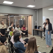 Foto mostra palestrante diante de plateia e tel&atilde;o ao fundo com o nome do Programa Impacta RS.