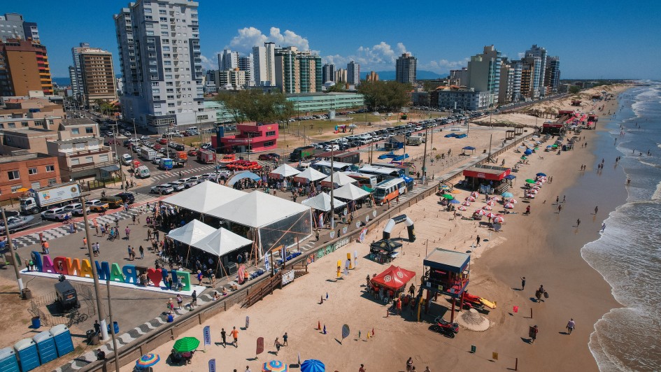 Foto a&eacute;rea mostra tendas da Opera&ccedil;&atilde;o Ver&atilde;o Total na beira da praia com mar em perspectiva.