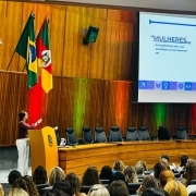 Foto secret&aacute;ria F&aacute;bia discursando no p&uacute;lpito diante de plateia.