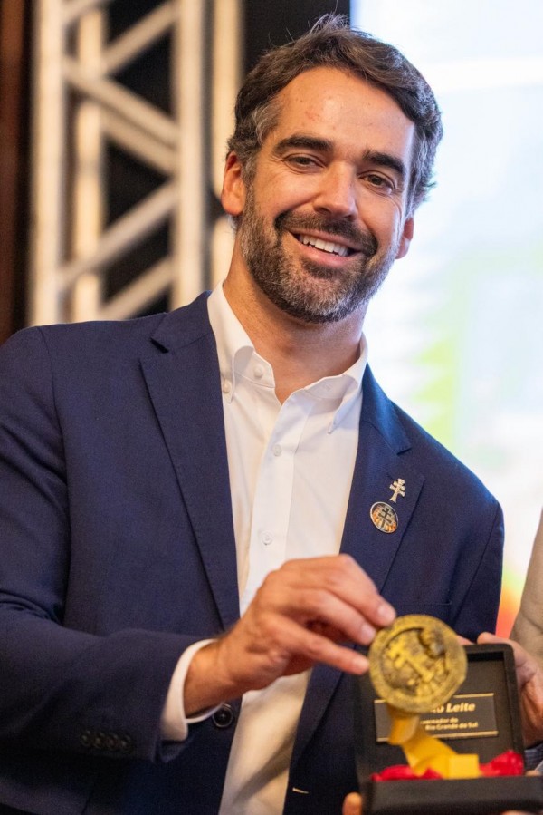 Foto mostra governador Eduardo Leite mostrando medalha conquistada. 