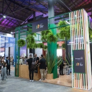 Foto mostra estande e pessoas circulando.