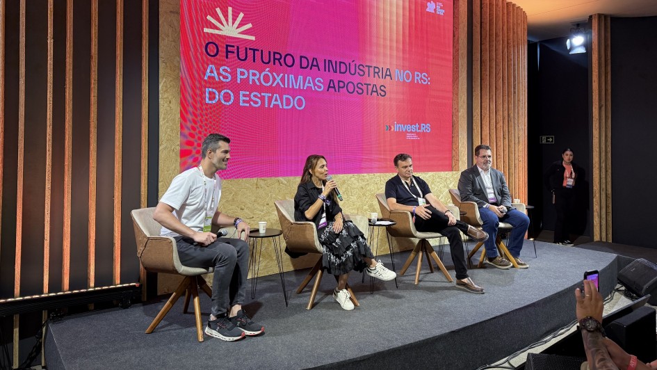 Foto mostra palestrante falando ao microfone, sentada ao lado de outros tr&ecirc;s painelistas. Atr&aacute;s, uma tela com o nome do painel.