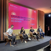 Foto mostra palestrante falando ao microfone, sentada ao lado de outros tr&ecirc;s painelistas. Atr&aacute;s, uma tela com o nome do painel.