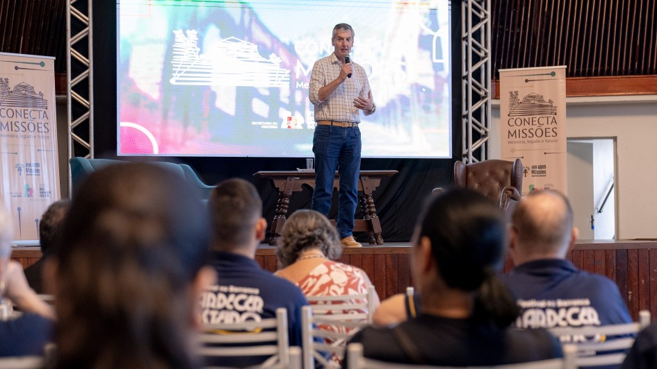 Secret&aacute;rio Loureiro falando durante evento no palco, com microfone, diante da plateia.