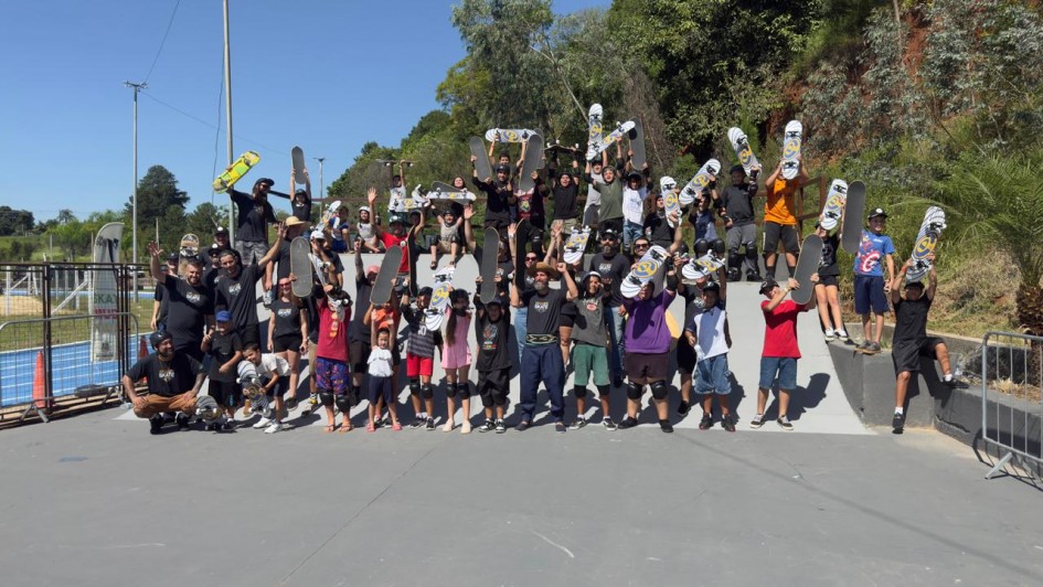 V&aacute;rios jovens seguram seus skates acima da cabe&ccedil;a &agrave; frente de uma grande rampa