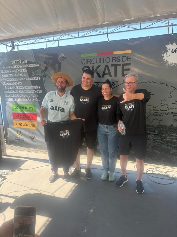 Quatro pessoas em frente a um grande painel onde está escrito Circuito RS de Skate