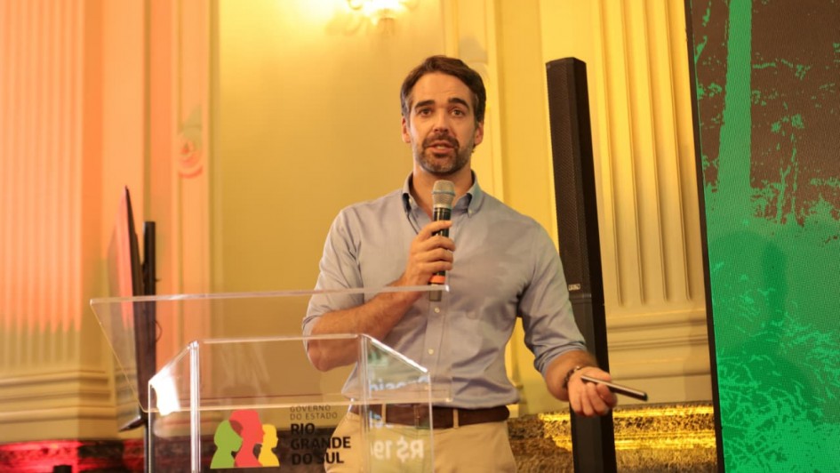 Governador Eduardo Leite discursando no p&uacute;lpito, com microfone na m&atilde;o. 