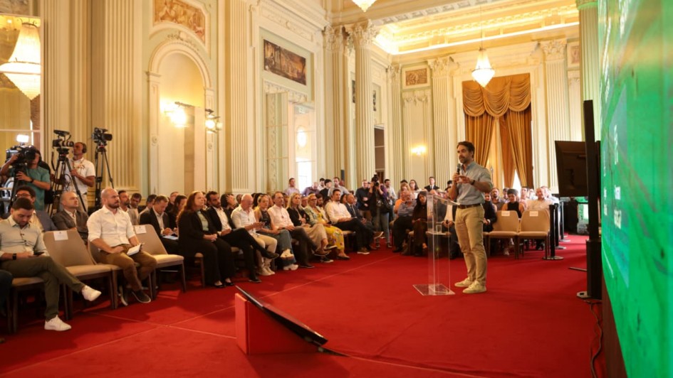 Governador Eduardo Leite discursando em p&eacute;, diante da plateia, no Pal&aacute;cio Piratini. 