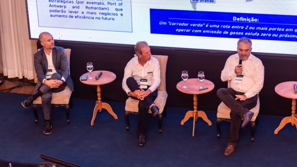 Foto mostra palestrantes no palco, sentados, durante debate.